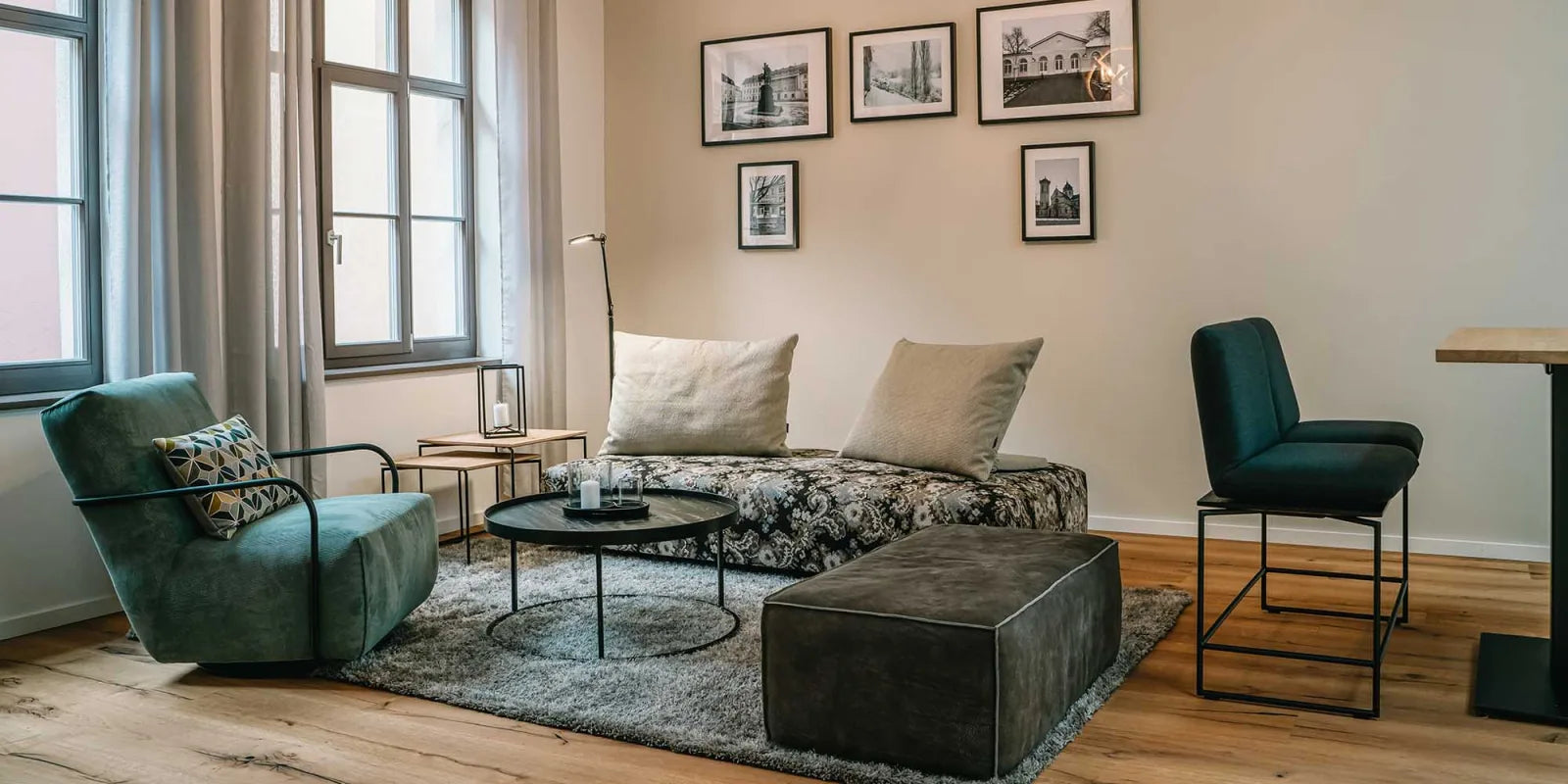 Modernes Wohnzimmer mit gemustertem Sofa, grünem Sessel und kleinen runden Beistelltischen